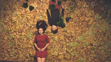 Young couple in leaves.
Slow motion. Top view.
Evening. The guy looks at the girl, and she looks up. They are serious and do not talk.
The camera moves over them from right to left.