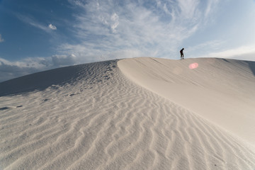 A man walking along a sand dune at White Sands National Monument in Alamogordo, New Mexico. 