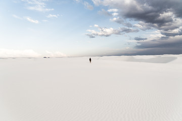 A man standing on top of a sand dune at White Sands National Monument in Alamogordo, New Mexico. 
