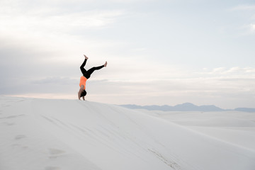 A woman flipping over a sand dune at White Sands National Monument in Alamogordo, New Mexico. 