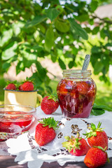Strawberry jam and juicy ripe strawberries on a wooden table in the garden on a summer sunny afternoon in a rustic style, the concept of gardening, healthy organic vitamin nutrition