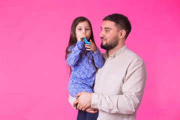 Naklejka premium Happy father with his baby daughter on pink background