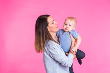 happy young mother with a baby child on pink background