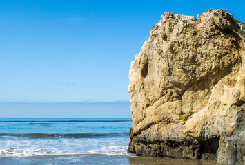 Fototapeta na wymiar jagged rock formation on the beach at the Pacific ocean in Malibu, California on a sunny summer day
