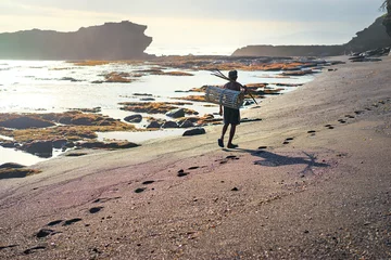 Fototapete Indonesien Fisherman carrying wicker basket  on the sunset beach. Bali Island, Indonesia.  © luengo_ua