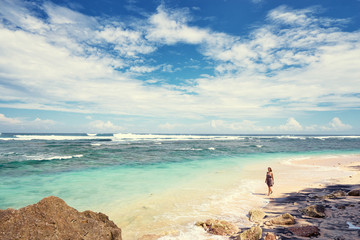 Sky and sea. Lonely young woman walking on ocean beach.