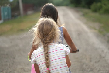 two small girls riding bikes in a quiet street, rear view