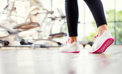 Sport concept. Close up of female feet in sneakers in gym.