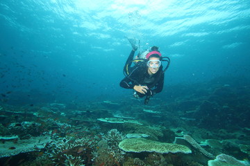 Female Scuba Diver and Colorful reef fish blue ocean and bright coral underwater