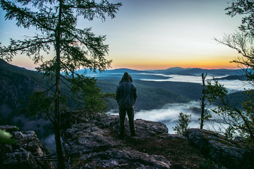 Man hiker standing back on peak of mountains and enjoy to see beautiful landscape view of rocks and mist coming up at summer morning.