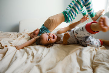 Children in soft warm pajamas playing in bed.