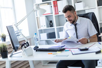 Fototapeta premium A man is sitting at the desk in the office and working with documents.