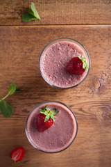 Two glasses of chocolate strawberry milkshake or cocktail on wooden table.  Strawberry chocolate smoothie with berries. Healthy drinks. overhead, vertical
