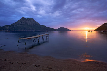 Pier and silend sea at the sunrise in the sandy beaches of Adrasan with a mountain view, Antalya