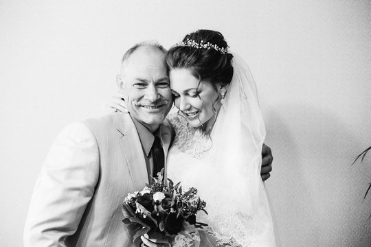 Happy Father With His Daughter, Who Gets Married And Holds A Wedding Bouquet In Her Hands