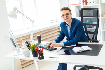 Young man sitting at desk in office and working on computer.