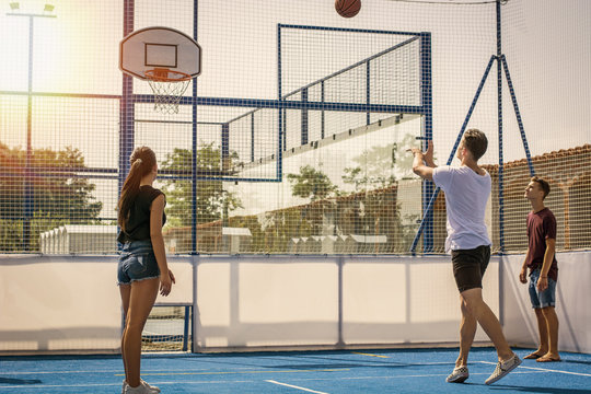 Young handsome men and women wearing shorts playing basketball on playground court