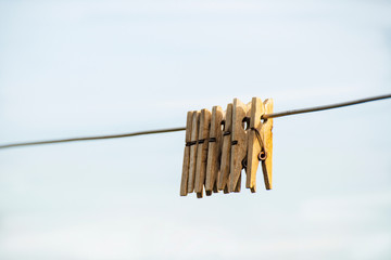 Wooden clothespins hanging on a steel wire on a light background