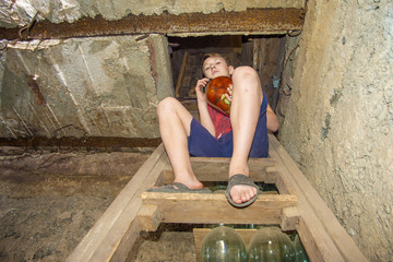 A boy is holding jars with vegetables and fruits in the basement with food, for storage for a long time.