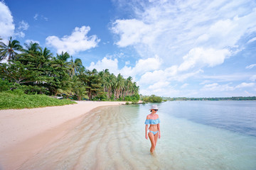 Vacation on the seashore. Young woman walking on the beautiful tropical white sand beach.