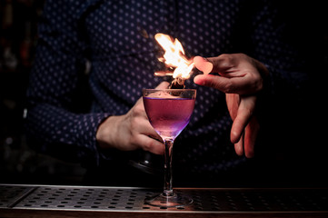 Barman making a sweet and fresh purple summer cocktail with a smoke note