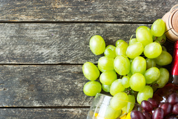 Bunches of fresh different ripe grapes and a bottle of red wine on a blue wooden textural surface. space for advertising text 