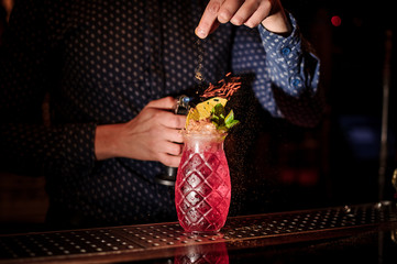 Bartender adding spices into the fresh and sweet strawberry mojito summer cocktail with a smoke note