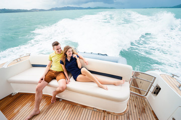 Romantic vacation and luxury travel. Young loving couple sitting on the sofa on the modern yacht deck. Sailing the sea.