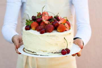 A woman is holding a cake with berries. Summer concept.