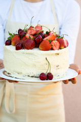A woman is holding a cake with berries. Summer concept.