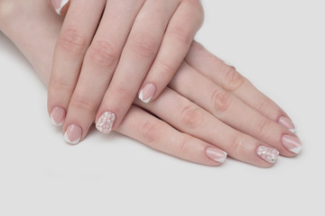 Manicure with rhinestones in the shape of hearts and pink balls on white and red nail Polish on a white background.