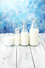 A jug of milk and glass of milk on a wooden table.