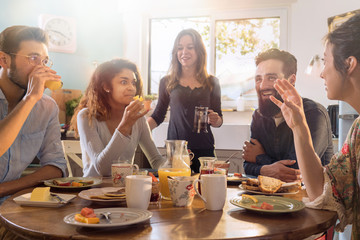 Group of multi-ethnic friends gathered around a table for breakfast