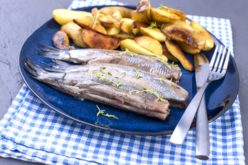 Fillet of herring on a plate and baked in the oven potatoes. Delicious traditional food of Holland. Dutch delicacy on a blue plate. Copy space