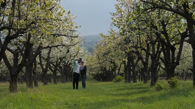A young couple in love stroll together through a beautiful forest with their pet dog. In slow motion.