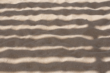 Sandy texture. Summer background. Patterns from the sun and shadows on sand