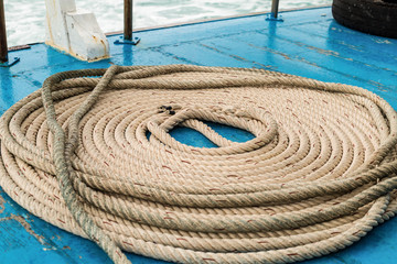 round folded braided thick natural beige rope on a blue deck background of a carton