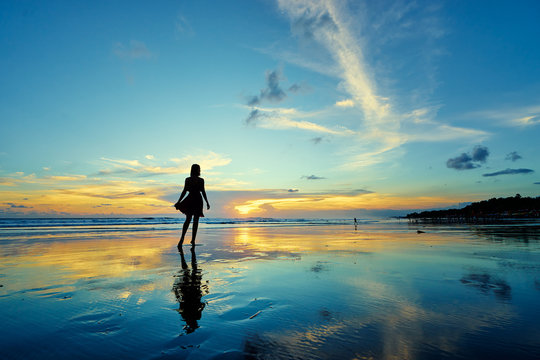 Sky And Sea. Beautiful Sunset. Silhouette Of Young Woman Walking On Ocean Beach.