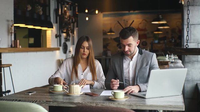 Male and female business colleagues working together on a hard problem at cafe