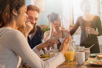 Group of multi-ethnic friends gathered around a table for breakfast