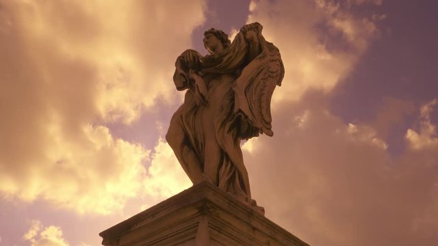 Statue of angel on bridge of historical center of Rome at sunset tracking shot