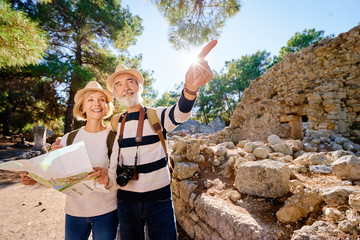 Family, age, tourism and travel concept. Happy senior couple with map at ancient sightseeing. - Powered by Adobe