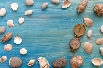 Fototapeta na wymiar Summer vacation background with copy space. Verious seashells and pebbles border frame and compass on blue wooden table background.
