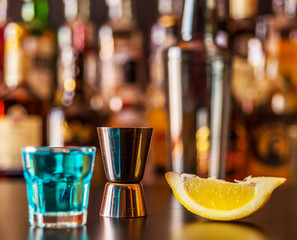 Popular blue drink shot kamikaze on the background of the bar with bottles, a refreshing drink