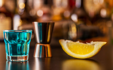 Popular blue drink shot kamikaze on the background of the bar with bottles, a refreshing drink