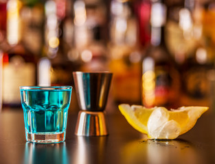 Popular blue drink shot kamikaze on the background of the bar with bottles, a refreshing drink