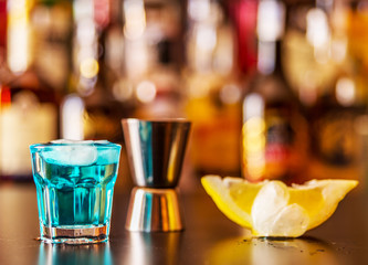 Popular blue drink shot kamikaze on the background of the bar with bottles, a refreshing drink