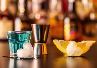 Popular blue drink shot kamikaze on the background of the bar with bottles, a refreshing drink