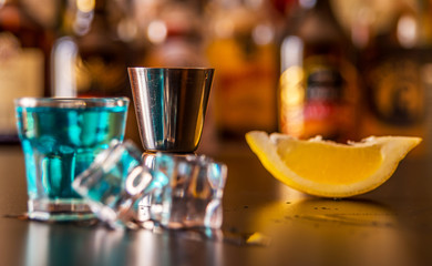 Popular blue drink shot kamikaze on the background of the bar with bottles, a refreshing drink