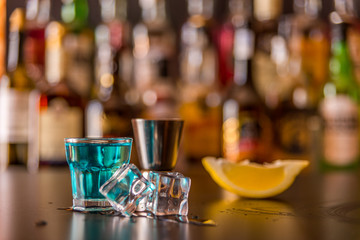 Popular blue drink shot kamikaze on the background of the bar with bottles, a refreshing drink